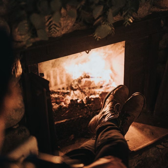 Homeowner warming themselves in front of a wood stove.